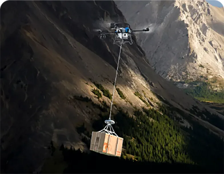 Dron EAVision J150 transportando una caja suspendida en terreno montañoso